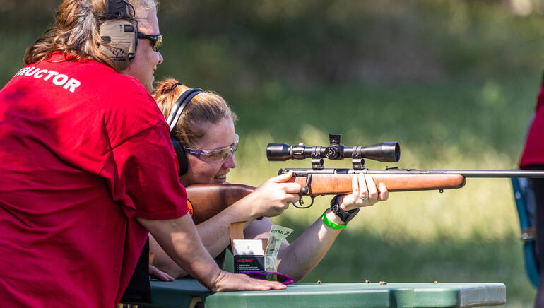 Girl learning to shoot rifle